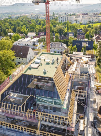 Construction of a multi-storey building with crane and scaffolding in a green urban environment,