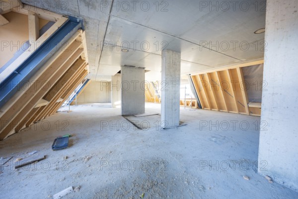 Unfinished interior with concrete pillars and wood paneling, light penetrating, carpentry