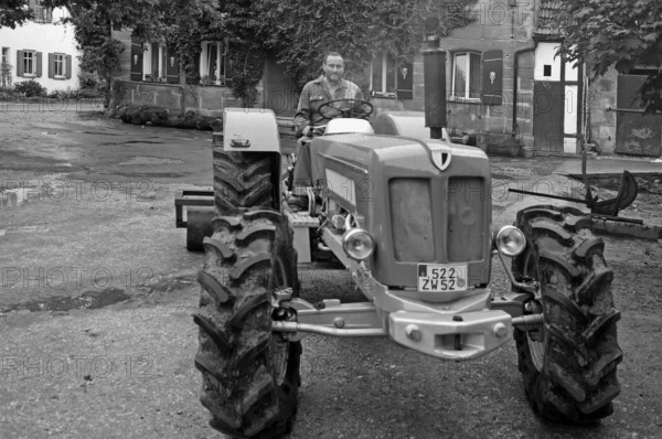 Farmer on his new Schlüter tractor in the yard, black and white, Tauchersreuth, Middle Franconia,