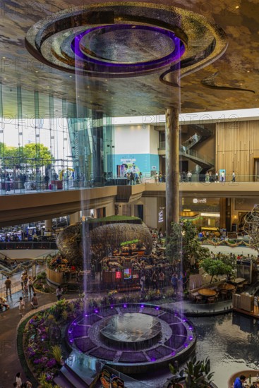 Artificial, brightly lit waterfall, magic waterfall, plunging from ceiling into a water basin,