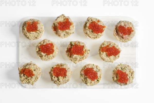 Twelve beautifully crafted tuna tartlets sit on a white platter. Each tartlet is filled with a