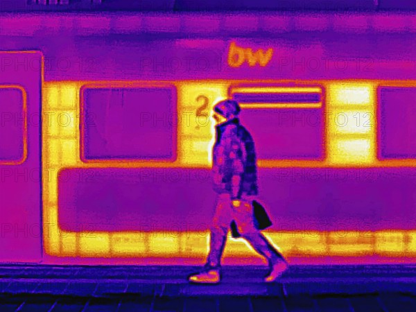 Locomotive in the train station. A man is walking on the platform. Thermal image or thermography,