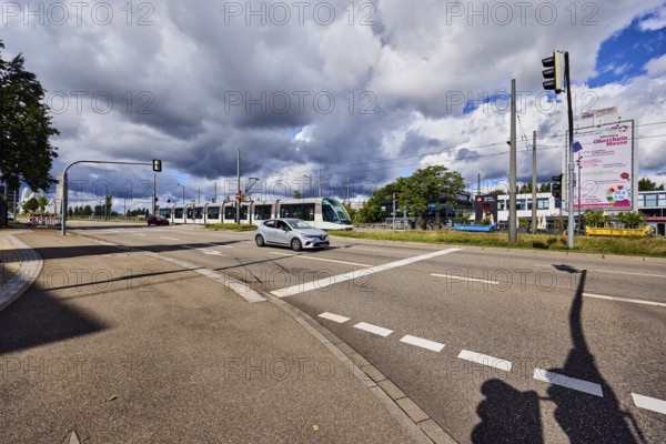 Tram, cars, street, sidewalk, lanes, cycle path, catenary masts, overhead line, central island,