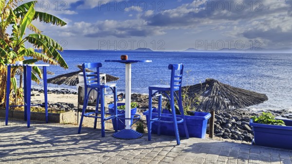 View of the sea from a terrace with blue chairs. A relaxed, sunny coastal scene, Playa Blanca