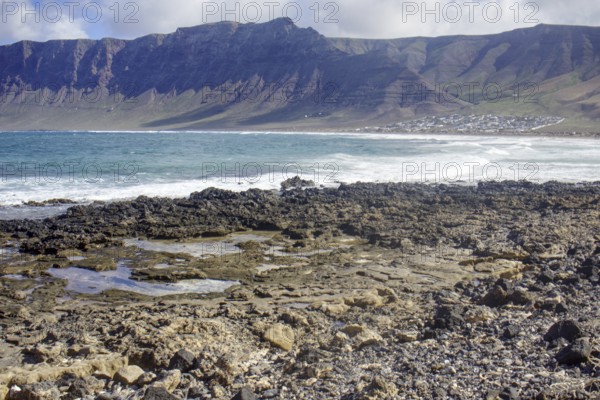 Rough coastal landscape with rocks in the foreground and mountains in the background (Risco de