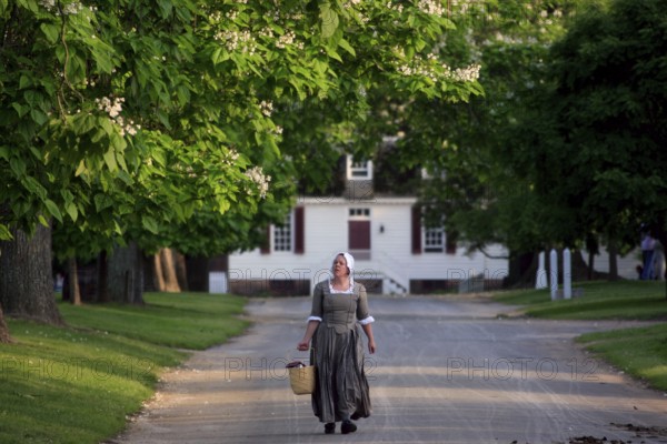 Woman wearing historical costume on a tree-lined street in Colonial Williamsburg, Williamsburg,