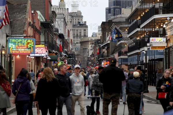 Bustling Bourbon Street at night with numerous passers-by and illuminated signs, New Orleans,