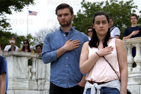 A man and a woman stand respectfully with their hands on their hearts during a ceremony, Washington