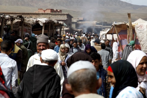 Bustling market in Msemrir with lots of people and stalls against a mountain backdrop, Msemrir,