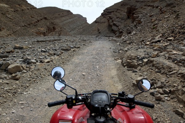 View from a motorcycle of a narrow, rocky path in a gorge, Tizgui n'Ouadda, Morocco