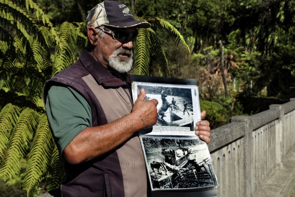 Man showing a book at the bridge in the thick forest on the Whanganui River, Whanganui River,