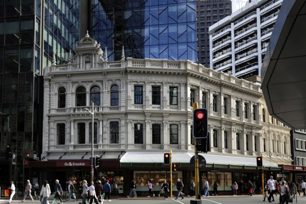 Busy intersection with historic façade contrasting with modern glass buildings on Lambton Quay,