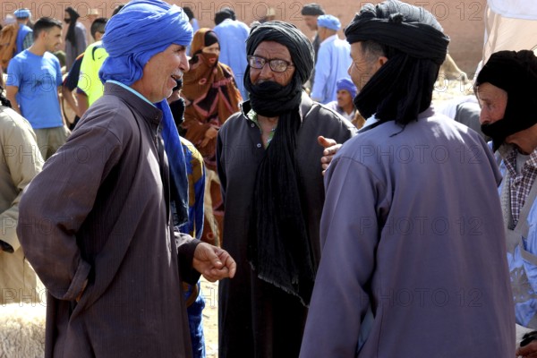 Three men in traditional clothing talking at a cattle market, Guelmim, Guelmim-Oued Noun, Morocco