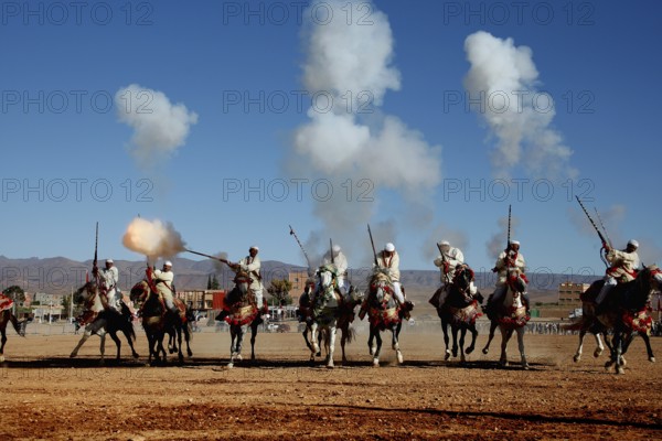 Group of riders fire guns and creates clouds of smoke during a traditional Fantasia ritual, El