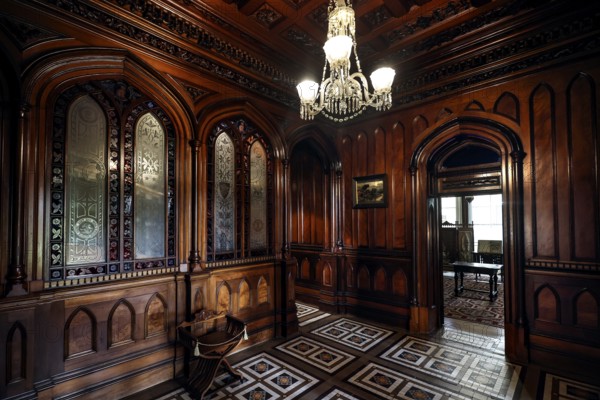 Antique foyer with intricate wood ornaments and a chandelier, Larnach Castle, Otago Peninsula, New
