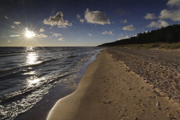 Sunset over sandy beach near Vitrupe, peaceful waves and golden horizon, Vitrupe, Latvia