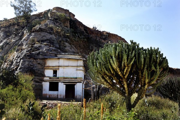 Entrance to Debre Mariam Krokor rock church in front of a steep rock face in natural surroundings,