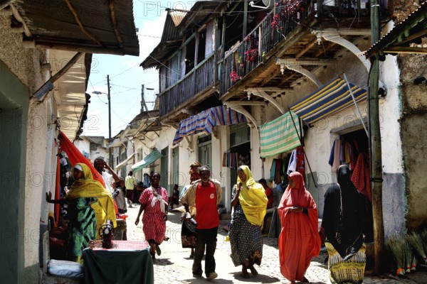 Busy alley in Harar with people in colorful costumes in bright sunshine, Harar, Oromia, Ethiopia