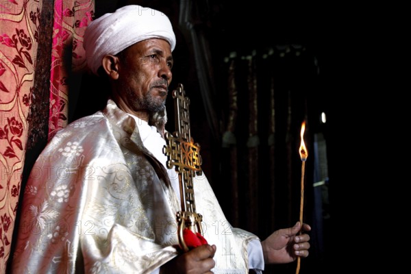 Priest with an ornate cross celebrates a ceremony in the Bete Meskel church. Expression of