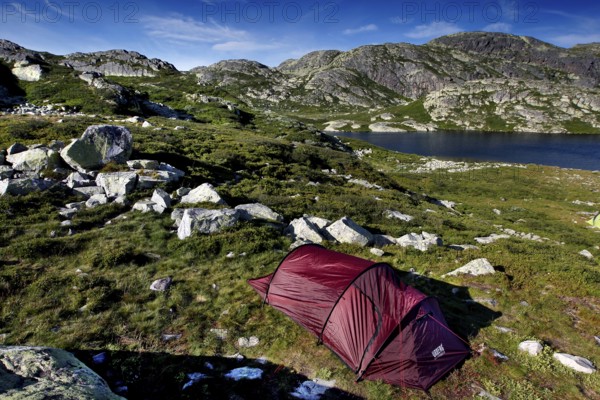 Red tent in mountainous seascape surrounded by untouched nature, Hardangervidda, Gausdal, Norway