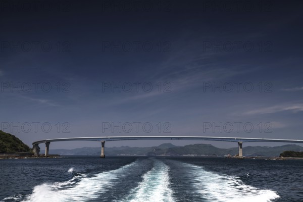 Bridge spanning the sea, with wave patterns in the foreground under clear sky, Nagasaki, Nagasaki,