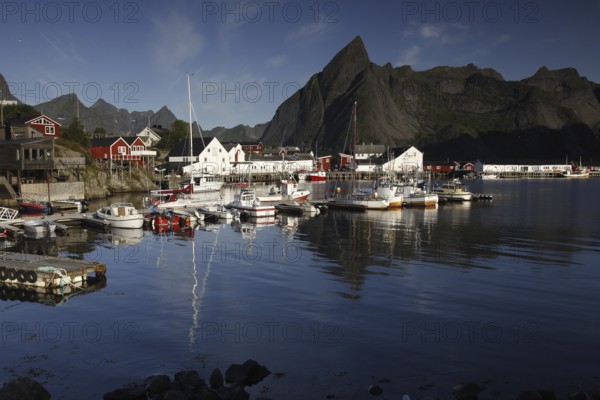 Sakrisøy harbour, where boats lie in calm water against a majestic mountain backdrop, Sakrisøy,