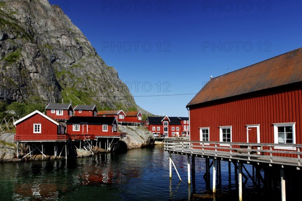 Red fishermen's houses in Sakrisøy against the majestic Lofoten mountains, Sakrisøy, Moskenesøy,