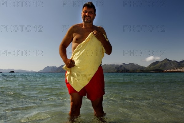 Summer day on Austvågøy beach with a man in the warm, clear water of Lofoten, Lofoten, Nordland,