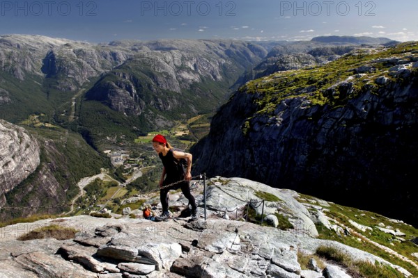 Hikers climbing Mount Kjerag with breathtaking mountain scenery in the background, Lysefjord,