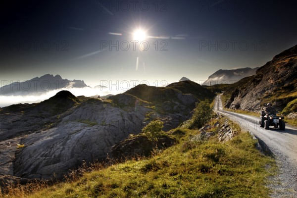 ATV rides through the rolling countryside of Lofoten under dazzling sunlight, Vestvågøy,