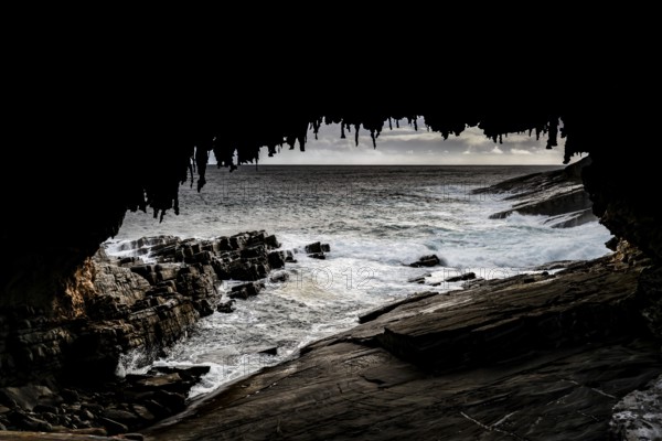 View of the ocean and rugged coastline through the dark cave of Admiral's Arch, Kangaroo Island,