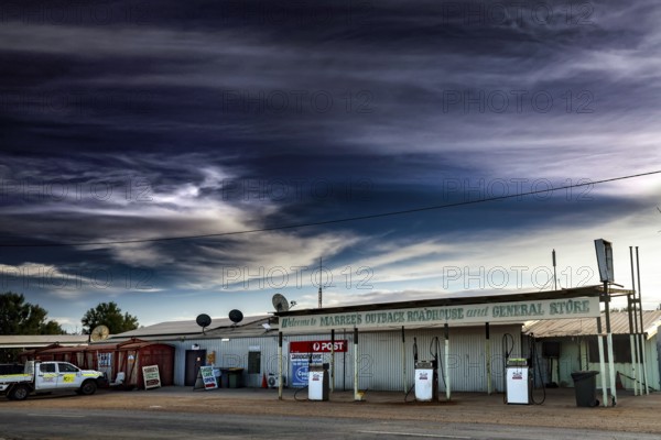 Abandoned gas station and storefront in Marree under dramatic sky, Marree, South Australia,