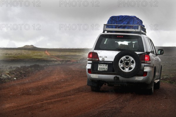 A Landcruiser drives along a track on the Sanetti Plateau under overcast skies, Bale Mountains,