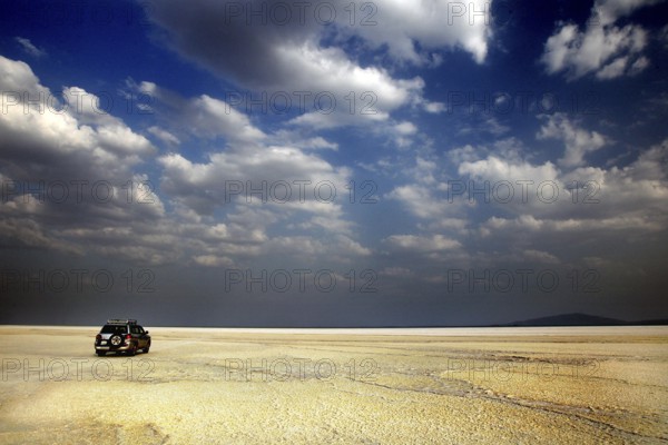 Land cruiser under cloudy sky in wide desert landscape, Dallol, Asale, Ethiopia