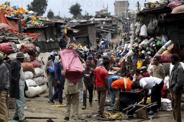 People carry large bags on their shoulders through the bustling Mercato in Addis Ababa, Addis