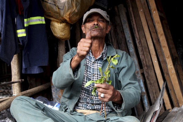Market scene in Mercato, Addis Ababa. A man points thumbs up while offering plants, Addis Ababa,