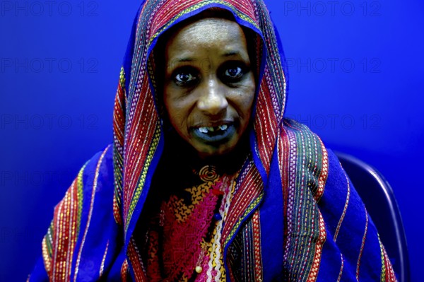 Female patient in intensive blue background and traditional clothing in hospital, Korhogo, CI, West