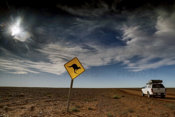 Kangaroo warning sign in an open, cloudy desert landscape near an off-road vehicle, Breakaways,