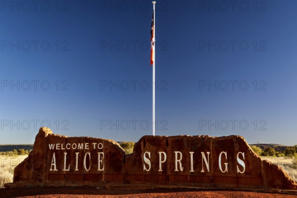 Alice Springs welcome sign with a flag against a clear sky, Alice Springs, Northern Territory,