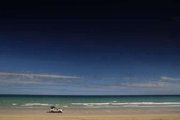 Vehicle on quiet shore of Cable Beach with clear, wide skies, Broome, Western Australia, Australia