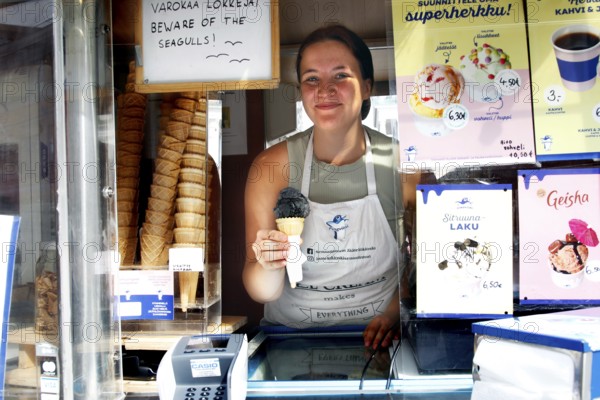 Saleswoman presents salmiac ice cream at an ice cream stand at Senaatintori, Helsinki,