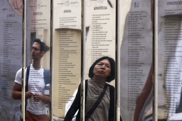 Passers-by look at the mirror installation with the Constitution of the Republic of Uzupis,