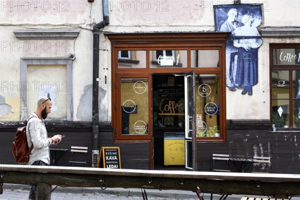 Passerby walks past a cafe in Uzupis, Vilnius, mural in the background, Vilnius, Vilnius County,