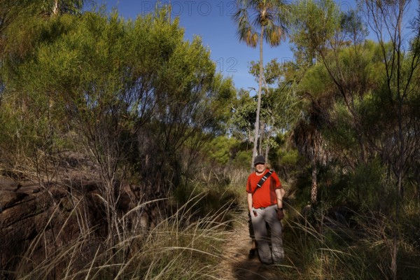 Man wearing red clothing wanders through dense landscape in Nitmiluk National Park, Nitmiluk