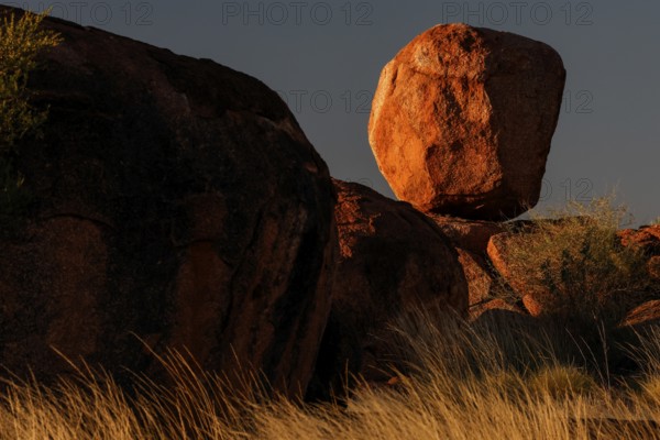 Balancing boulder in the desert, dramatically illuminated by the evening sun, Devil's Marbles,