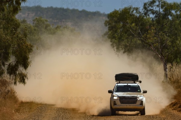 A four-wheel drive vehicle drives through clouds of dust on the unpaved Gibb River Road, Gibb River