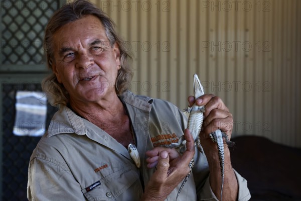 A man presents a baby crocodile in Malcolm Douglas Crocodile Park, Broome, Western Australia,