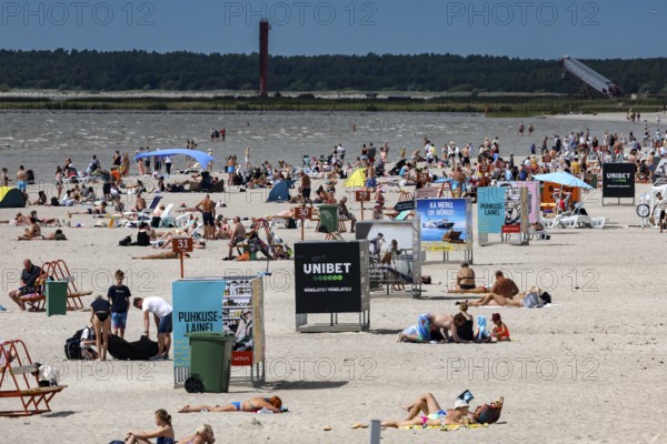 Busy sandy beach with lots of people and advertising signs under clear skies, Pärnu, Pärnu County,