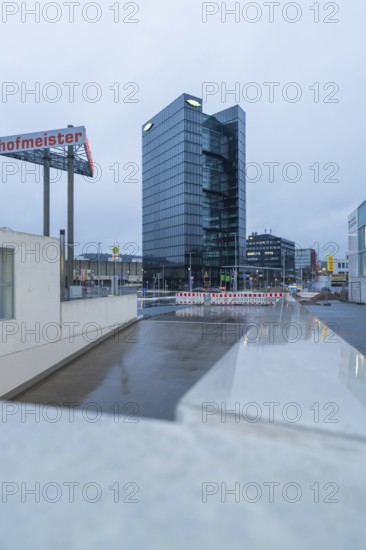 Modern Bitzer high-rise building at dusk with glass façade and a construction site in the