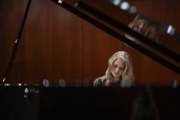 Young woman, pianist, with concentrated facial expression playing on a Steinway & Sons grand piano,